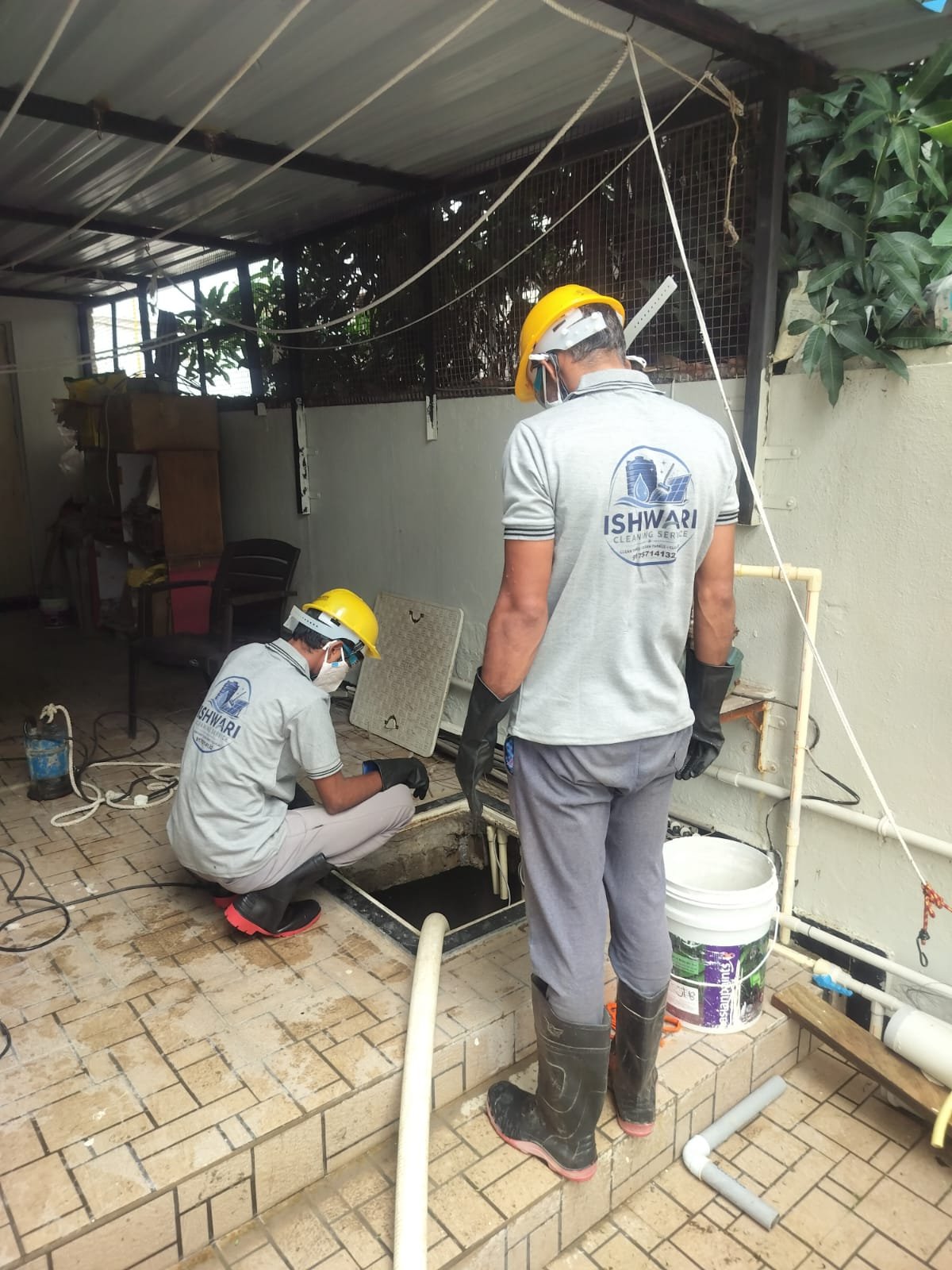 Two uniformed technicians working beside an underground tank opening