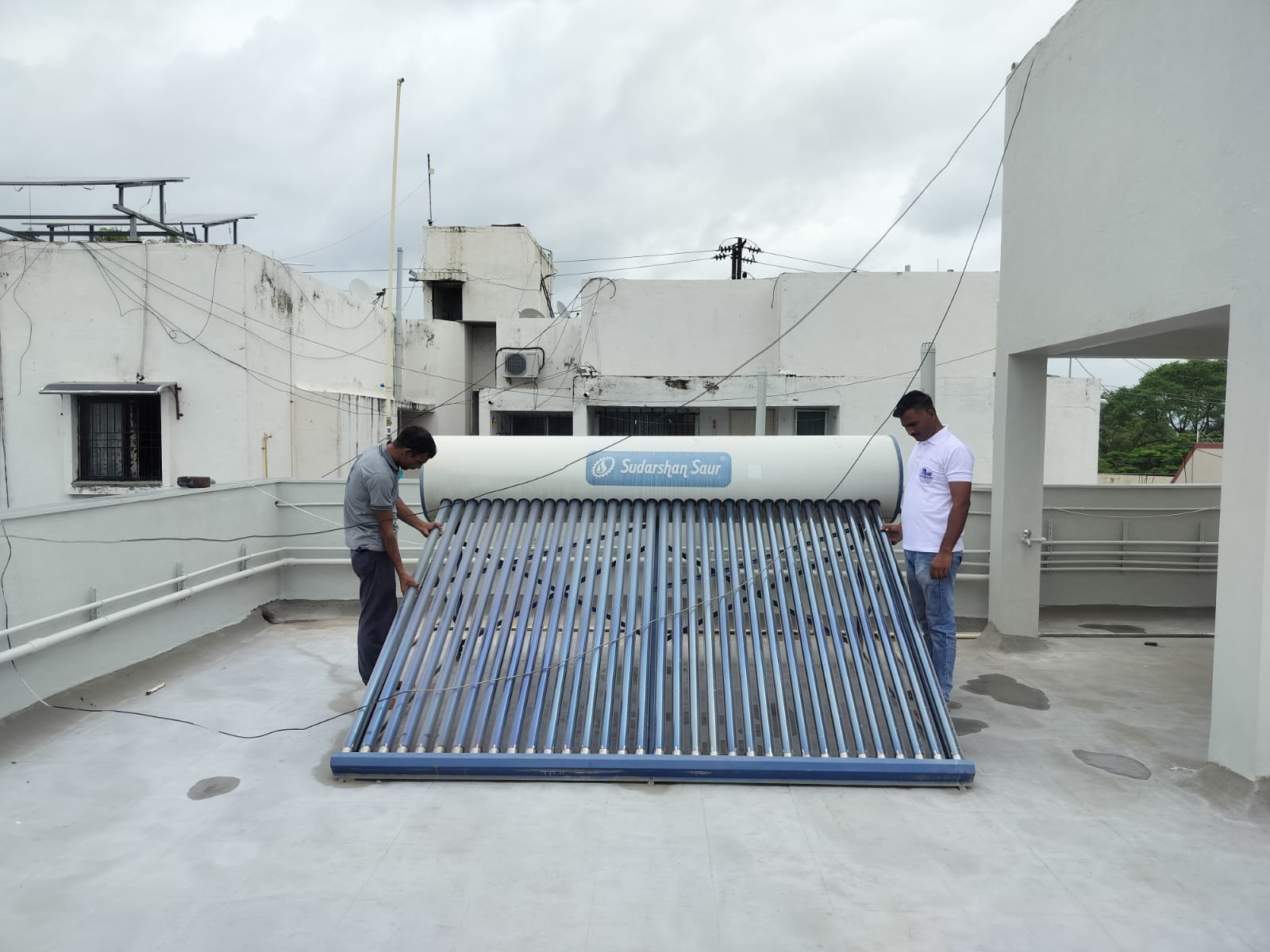 Technicians inspecting the collector tubes of a rooftop solar water heater