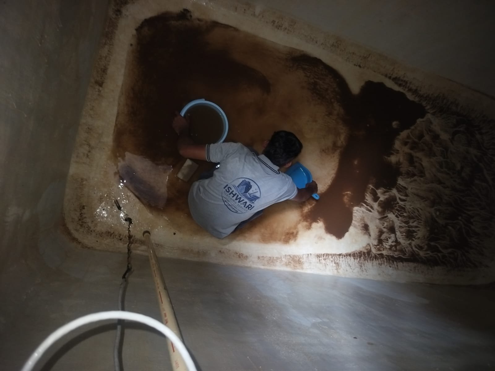 Technician removing accumulated dirt from inside a water tank